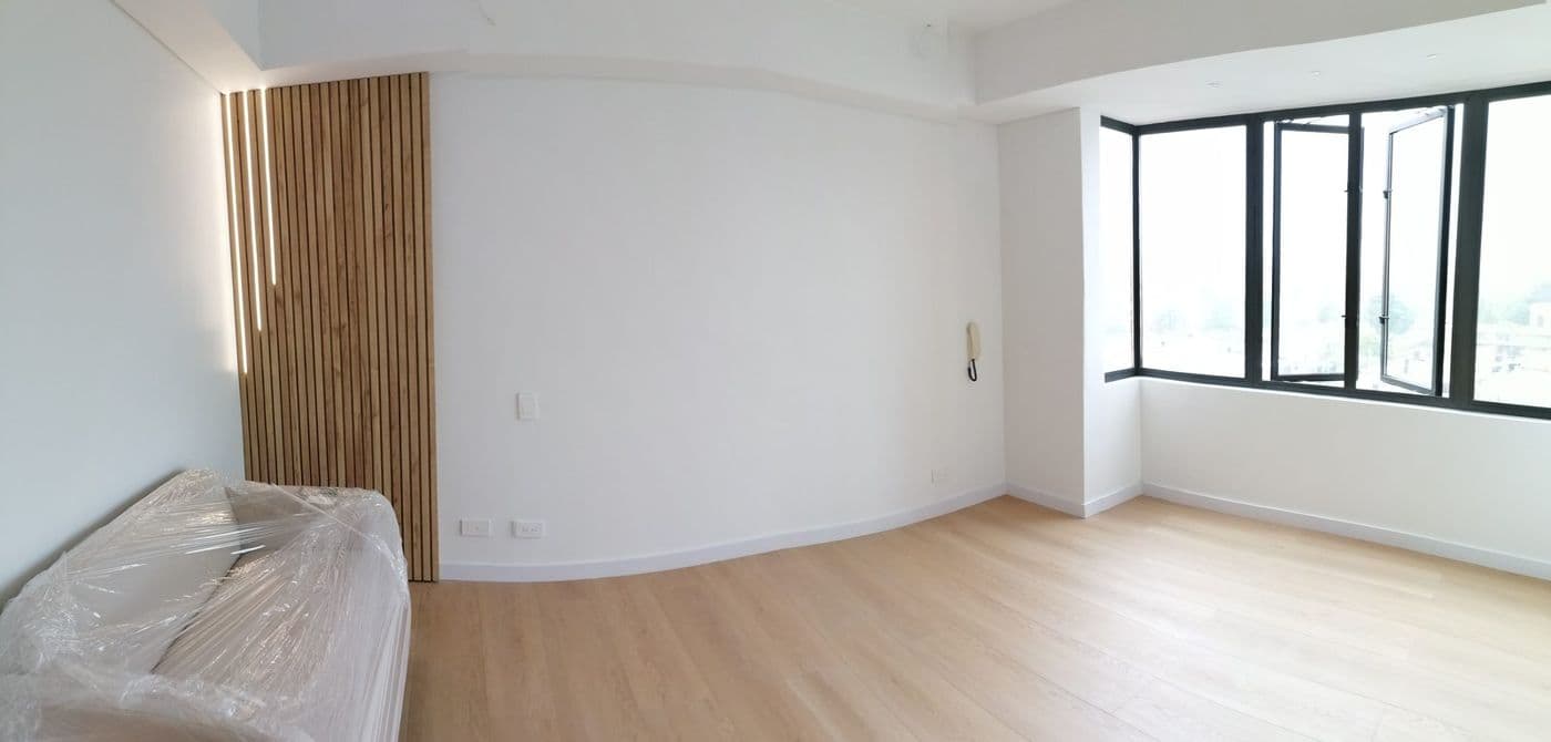 Sala con panel de listones de madera con luz, ventanería negra y piso de madera clara